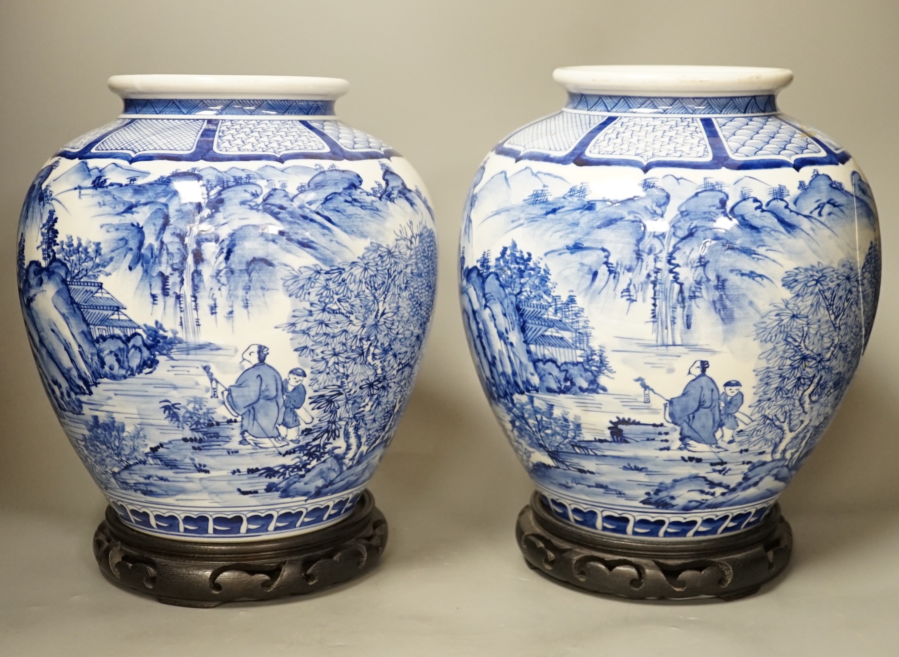 A pair of large Japanese blue and white vases, on wood stands, 26cms high of including stand.